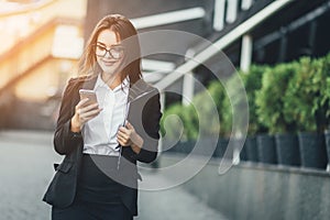 Portrait of cheerful young woman talking on smartphone and laughing outdoors. Happy beautiful caucasian woman using