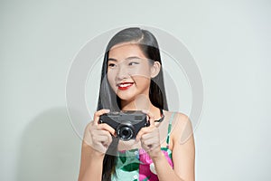 Portrait of cheerful young woman using camera for taking photos