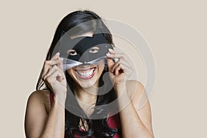 Portrait of a cheerful young woman wearing eye mask over colored background