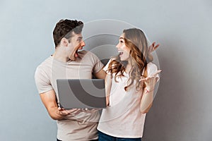 Portrait of a cheery happy couple holding laptop computer