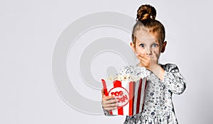 Portrait of a cheery pretty girl holding plastic cup and eating popcorn isolated over white background