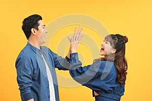 Portrait of a cheery young couple giving high five over yellow background