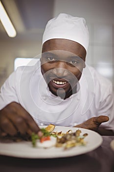 Portrait of chef garnishing meal on counter in commercial kitchen