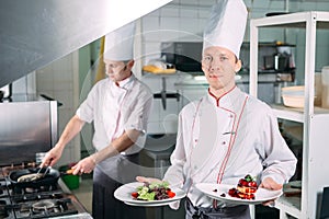 Portrait of the Chef in the kitchen of the restaurant with a ready-made dish Foie Gras.