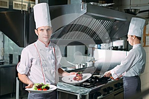 Portrait of the Chef in the kitchen of the restaurant with a ready-made dish Foie Gras.