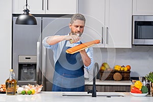 Portrait of chef man in cook apron preparing fresh natural meal salmon with olive oil at kitchen. Handsome cheerful chef