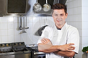 Portrait Of Chef Wearing Whites Standing By Cooker In Kitchen