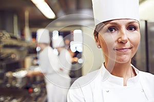 Portrait, chef and woman in kitchen for cooking, catering and presentation of food in restaurant. Professional, culinary