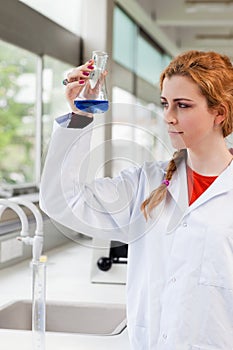 Portrait of a chemist looking at a blue liquid