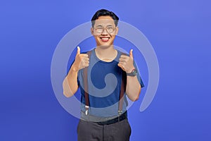 Portrait of cherful Asian man showing thumbs up or sign of approval isolated on purple background photo