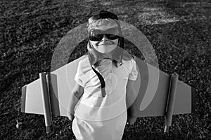 Portrait of child boy dreams and travels. Boy with airplane toy outdoors. Happy child playing with toy airplane outdoors