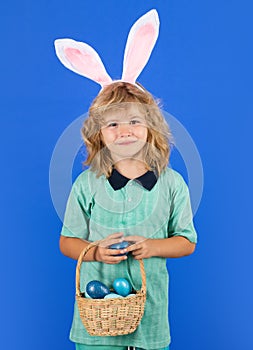 Portrait of child with bunny ears hold easter basket with easter eggs, isolated on studio background. Funny easter bunny