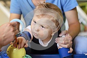 Portrait of a child with cerebral palsy on physiotherapy in a children therapy center. Boy with disability has therapy by doing