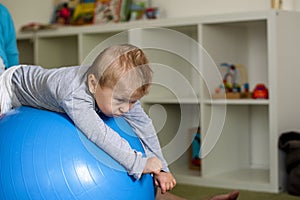 Portrait of a child with cerebral palsy on physiotherapy in a children therapy center. Boy with disability has therapy by doing