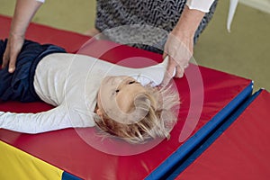 Portrait of a child with cerebral palsy on physiotherapy in a children therapy center. Boy with disability has therapy by doing