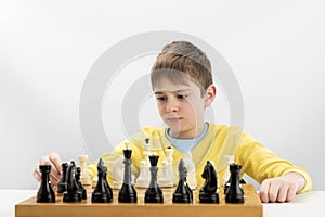 Portrait of child during chess game. Boy plays chess and thinks intently about the next move. Isolation on white background