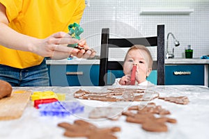 Portrait of a child chewing a cookie cutter. Mother makes gingerbread. Mother& x27;s Day concept and cooking festive home