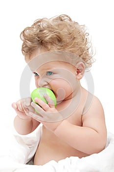 Portrait of a child curly hair eats a green Ð°pple