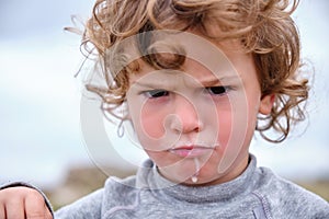 Portrait of a child with a frown and a milk-stained mouth