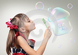 Portrait of Child girl blowing soap bubble forming house, habita