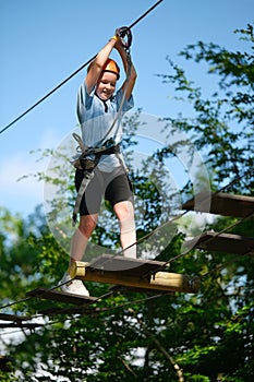Portrait of child girl having fun at outdoor extreme adventure rope park. Active childhood, playing outdoors.