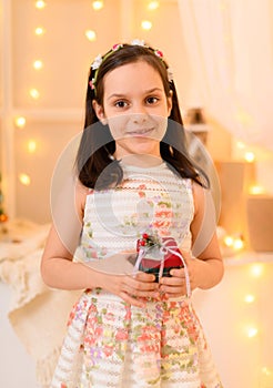 Portrait of a child girl in home interior decorated with lights and holiday gifts