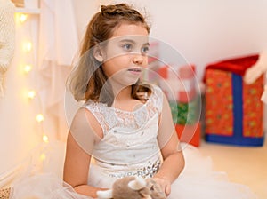 Portrait of a child girl in home interior decorated with lights and holiday gifts