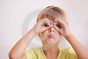 Portrait, child or kid and hands like glasses, playful and goofy on white background. Young boy or toddler, mischievous