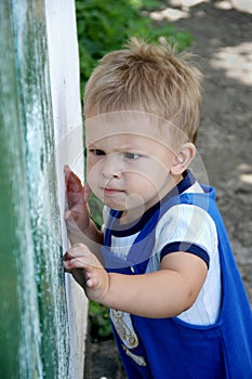 Portrait of child. Little boy focused, trying to open the door. Outdoor. photo