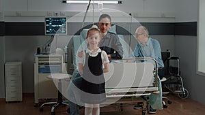 Portrait of child and mother visiting old patient in hospital ward bed