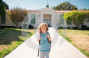 Portrait of child pupul with rucksacks in the park near school. Schoolboy with backpacks outdoors. School building