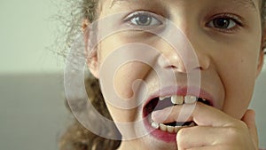 Portrait of a child with a smile on his face loosens his milk tooth. Cute little girl of 8-9 years old is losing milk