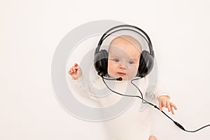 Portrait of a child on a white background with headphones. stay home, coronavirus 19. Baby 6 months listening to music. Space for