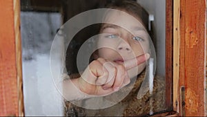 Portrait of child in the window. The boy face close up child through the glass.