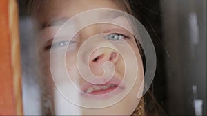 Portrait of child in the window. The boy face close up child through the glass.