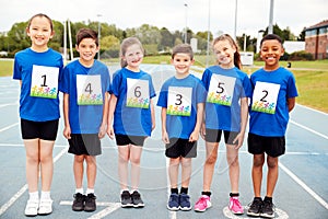 Portrait Of Children On Athletics Track Wearing Competitor Numbers On Sports Day