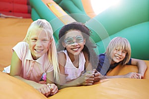 Portrait Of Children On Inflatable Slide At Summer Garden Fete