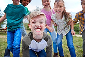 Portrait Of Children On Outdoor Activity Camping Trip Pulling Faces Having Fun Playing Game Together