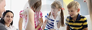 Children playing fun card game with adults, brothers and sisters having fun at home with parents