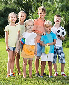 Portrait of children standing with toys on green meadow in park