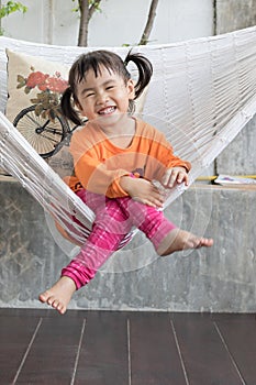 portrait of children toothy smiling and relaxing in clothes cradle at home living terrace