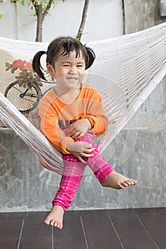 portrait of children toothy smiling and relaxing in clothes cradle at home living terrace