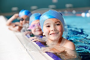 Portrait Of Children In Water At Edge Of Pool Waiting For Swimming Lesson