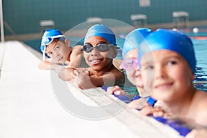 Portrait Of Children In Water At Edge Of Pool Waiting For Swimming Lesson