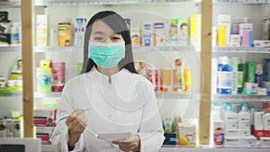 Portrait of chinese female druggist in protective facial mask working in pharmacy