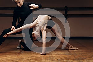 Portrait of a choreographer& x27;s teacher helping a little girl to pose correctlyin a dance studio, dimmed light. place