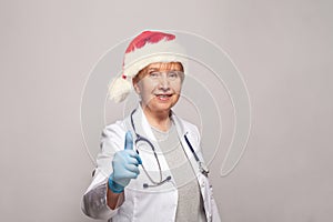 Portrait of Christmas doctor or nurse Santa with thumb up on white background