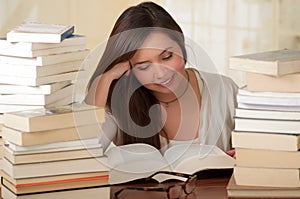 Portrait of clever student with open book reading in college library