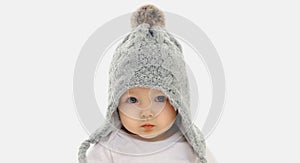 Portrait close up of baby wearing winter knitted gray hat over a white background