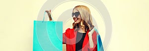 Portrait close up beautiful happy smiling young woman with colorful shopping bags wearing a red business blazer on background